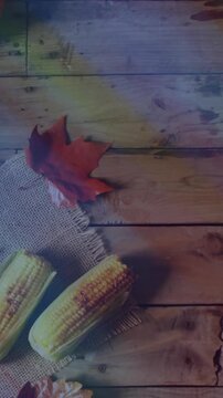 Thanksgiving table set with turkey, corn, and autumn leaves on wooden surface