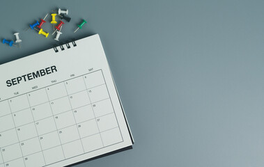 Top view of desk calendar for september with colorful push pins on gray background, planning, scheduling and reminder concept. © Ohayo