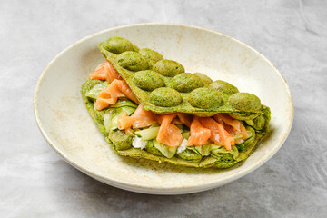 Fresh green matcha waffle sandwich with salmon and vegetables on a light background