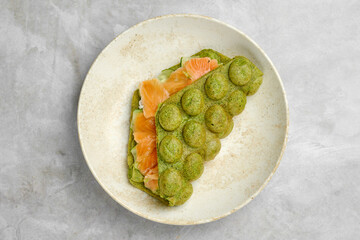 Delicious green tea pancake filled with fresh salmon served on a white plate