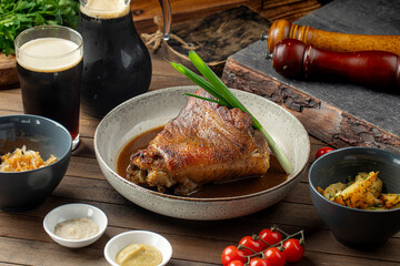 Roasted pork knuckle with sauces cabbage and potatoes on wooden table