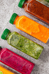 Colorful detox juices in plastic bottles on concrete background