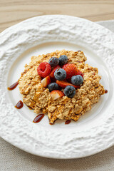 Crumble dessert with berries on white ceramic plate