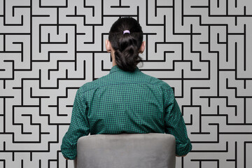 A woman is standing near a wall with a drawing of a labyrinth. Brainstorming, thinking,...