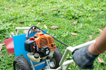 Gardener carefully mowing the green lawn with a modern lawn mower on a sunny day outdoors.