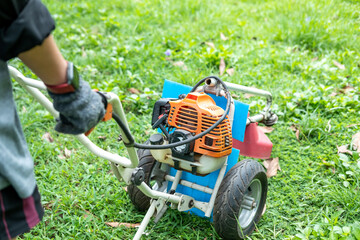 Gardener carefully mowing the green lawn with a modern lawn mower on a sunny day outdoors.