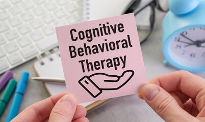 A hand holding a pink card that says Cognitive Behavioral Therapy
