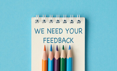 A notebook with pencils on it that says We need your feedback
