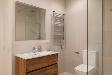 Bathroom with wood vanity, chrome towel warmer, glass shower and beige tiled walls