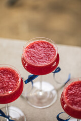 Three red cocktails in glasses with blue ribbons on the counter