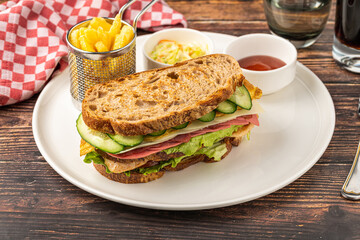 Club sandwich with lettuce, cheese, cucumber, and deli meats on a plate