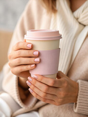 Close up of woman hands holding pastel coffee cup, showcasing beautifully manicured nails. soft colors and cozy attire create warm and inviting atmosphere