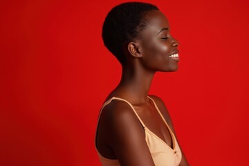 Side view of a pleasant African woman with short hair in a studio shot with a red background