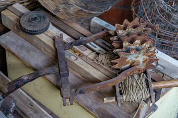 Rusty metal gears and old agricultural tools placed on a wooden table. Rustic, industrial...