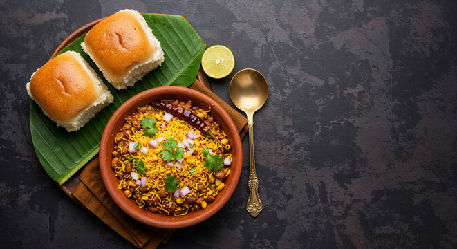 Top view flat lay of authentic Indian Misal Pav, a savory moth bean snack with farsan topping and pav bread