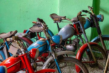 Colorful vintage mopeds from the communist era parked by a green wall. Well-preserved retro...
