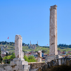 Ancient ruins of Agora &Ouml;ren Yeri in Izmir, with arched stone structures and distant mosques rising in the background skyline, Izmir, Turkey.