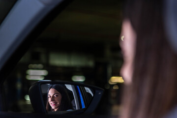 Businesswoman driving and smiling in rear view mirror