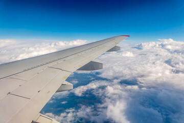View from the airplane window at a beautiful cloudy sky and the airplane wing