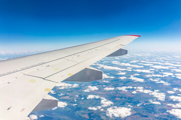View from the airplane window at a beautiful cloudy sky and the airplane wing