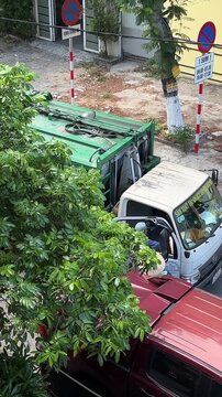 garbage truck car picks up trash behind tree asia vietnam. High quality 4k footage