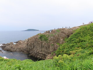 Fototapeta premium Tourists walking along rugged cliffs of Tojinbo on Japan Sea coast