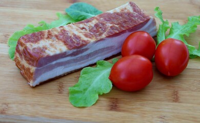 A large, thick piece of bacon on a cutting board.