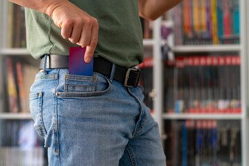 A man's hand is pulling a card from his jeans pocket.