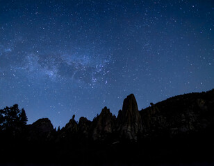 A breathtaking view of the Milky Way stretching above jagged mountain peaks, capturing the raw beauty of a starry night in untouched nature.
