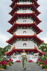 Fototapeta premium young woman stands on the steps leading up to a multi-tiered traditional Chinese pagoda