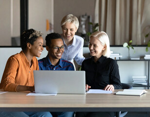 Diverse group of colleagues collaborating enthusiastically around a laptop in a modern office setting