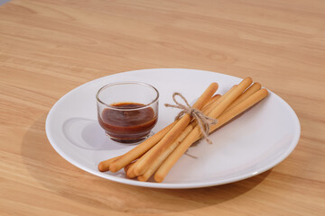 pack of breadsticks with ketchup dipping sauce in white dish on wood table