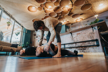 People practicing yoga in a studio with an instructor assisting in poses. The ambiance is enhanced...