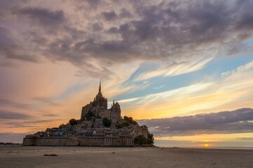 Sunset with a historic building. Famous Mont-Saint-Michel in the evening at low tide day with a...