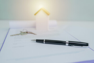 Real estate contract with pen and miniature houses on wooden desk, representing property agreement,...