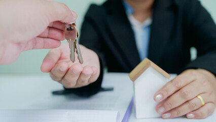 Real estate agent handing over house keys to client after signing contract, symbolizing property sale, rental, or new home ownership.