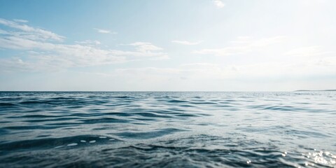 Fototapeta premium Calm ocean waves reflect the clear blue sky under soft clouds during the late afternoon
