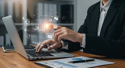 A businessman in a suit works on a laptop, interacting with a futuristic virtual interface displaying data analytics and business management icons.