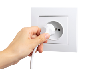 A hand holding a power plug halfway inserted into a socket