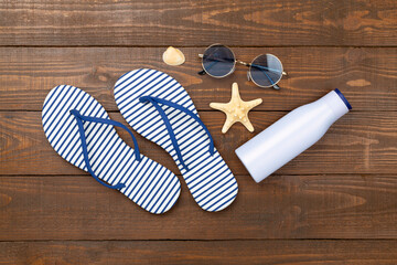 Striped blue flip flops with accessories on wooden background, top view