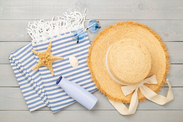 Beach towel with summer accessories on wooden background, top view