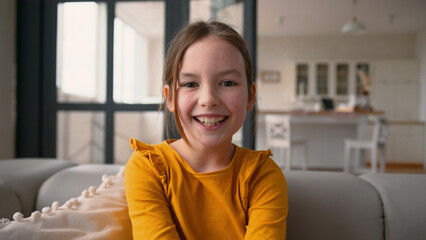Happy cheerful little Caucasian girl kid portrait daughter laugh amaze schoolgirl winning rejoicing...