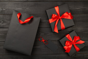 Black shopping bag and gift boxes on wooden background, top view. Black Friday concept