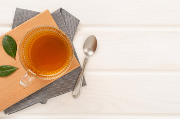 Cup of tea with dry and fresh leaves on wooden background, top view
