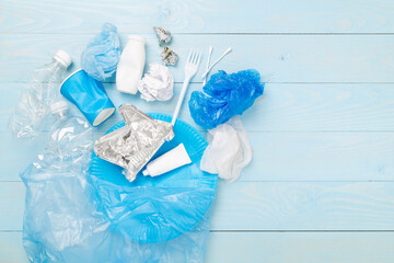 Bag with unsorted waste on wooden background, top view