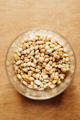 Top view of glass jar with pine nuts on wooden table, close-up.