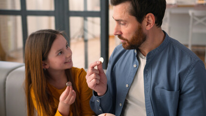 Happy Caucasian family little schoolgirl child girl daughter kid saving money at home guy parent dad male father man put coins in piggy bank savings economy financial education invest charity donation