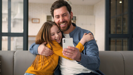 Happy smiling Caucasian family father man dad hold mobile phone child daughter winning scream rejoice male parent give high five little kid girl cuddle success victory at home great results happiness