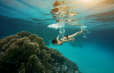Asian woman free diving with fins underwater in clean ocean