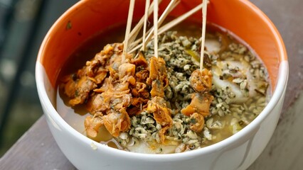 Authentic Lontong Kupang and Sate Kerang. A traditional clam soup with rice cakes in savory shrimp paste broth. Famous Indonesian street food specialty from Sidoarjo, East Java